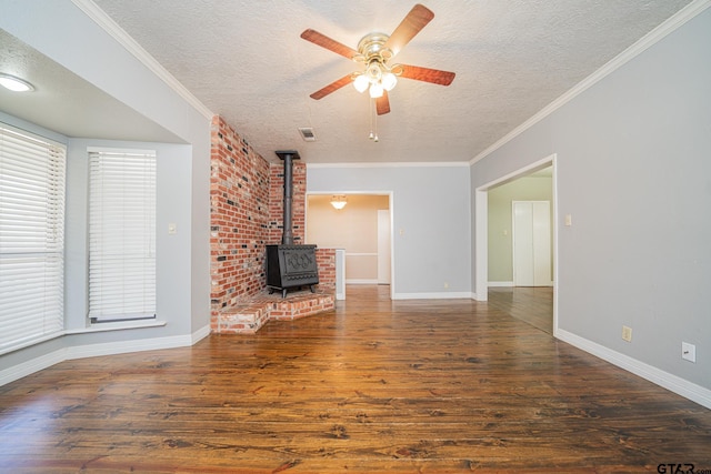 unfurnished living room featuring ceiling fan, a wood stove, a textured ceiling, and crown molding