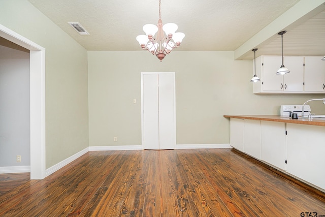 unfurnished dining area featuring a textured ceiling, a chandelier, dark hardwood / wood-style flooring, and sink