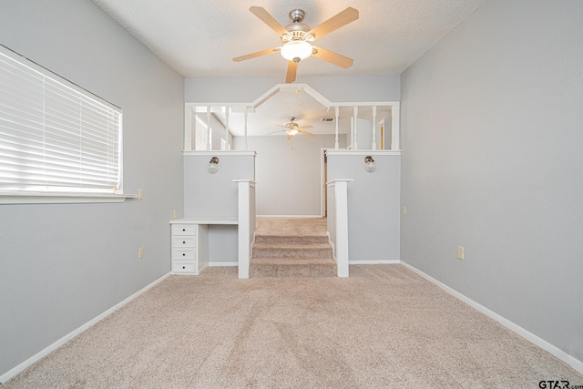 unfurnished living room with a textured ceiling, ceiling fan, and light colored carpet