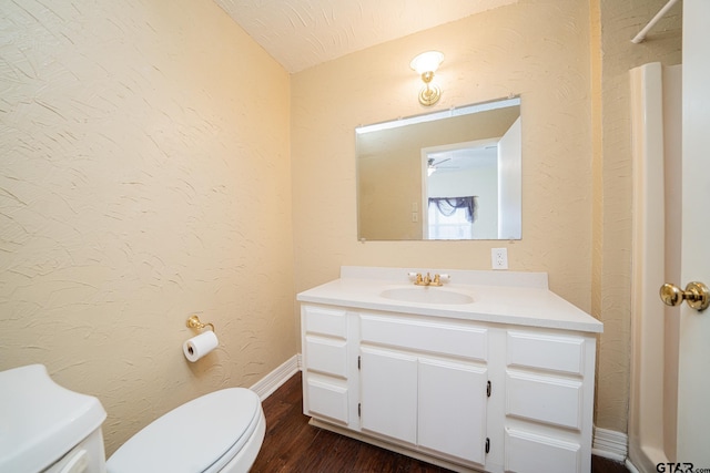 bathroom featuring lofted ceiling, vanity, toilet, wood-type flooring, and a textured ceiling