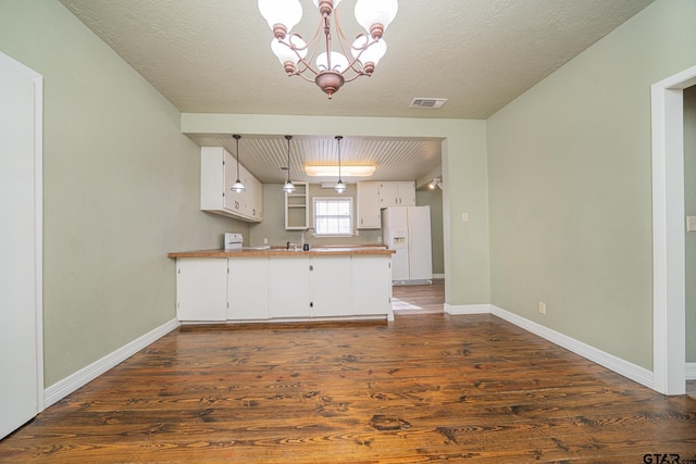 kitchen with decorative light fixtures, white fridge with ice dispenser, white cabinets, and a notable chandelier