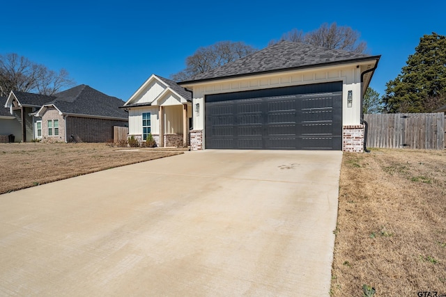 view of front facade featuring a garage, driveway, board and batten siding, and fence