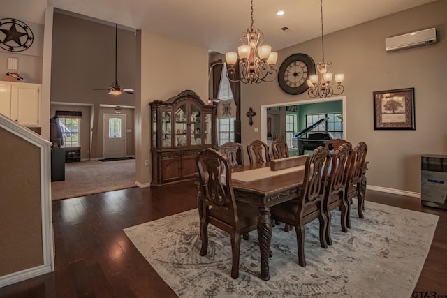 dining space with an AC wall unit, dark hardwood / wood-style flooring, ceiling fan with notable chandelier, and a high ceiling