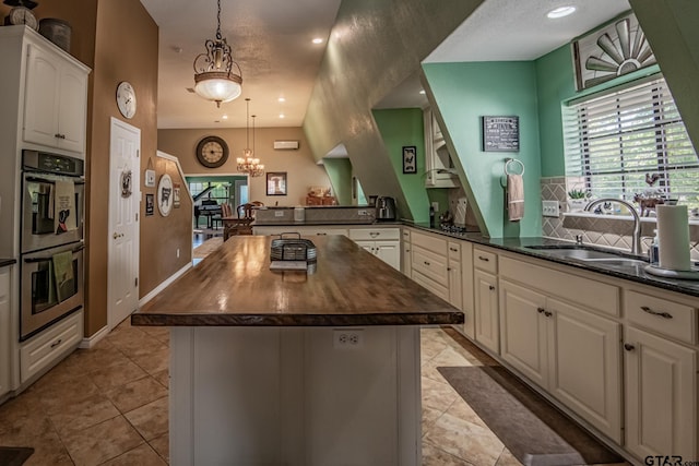 kitchen featuring pendant lighting, a center island, sink, and double oven