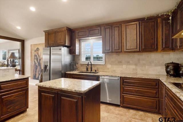 kitchen with sink, plenty of natural light, lofted ceiling, a kitchen island, and appliances with stainless steel finishes