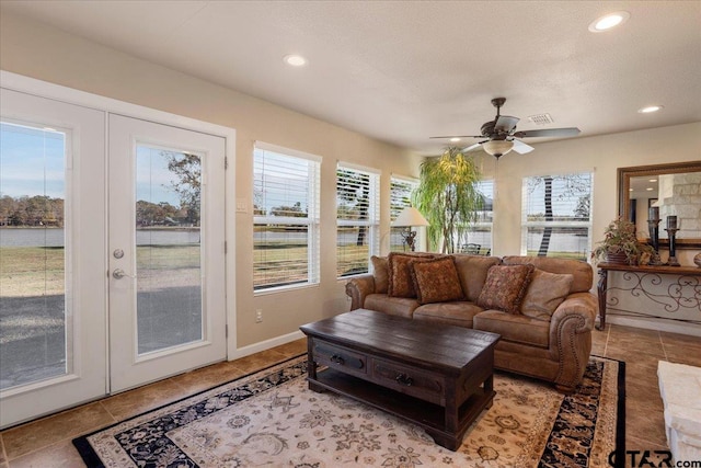 living room featuring a textured ceiling, ceiling fan, a healthy amount of sunlight, and french doors