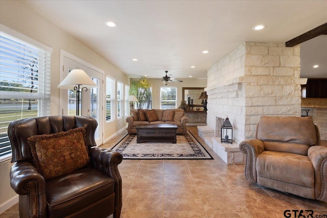 living room with a fireplace, ceiling fan, and plenty of natural light