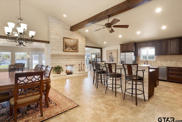 kitchen with stainless steel appliances, pendant lighting, a breakfast bar area, a fireplace, and dark brown cabinets