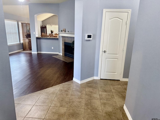 hall featuring light tile patterned flooring and lofted ceiling