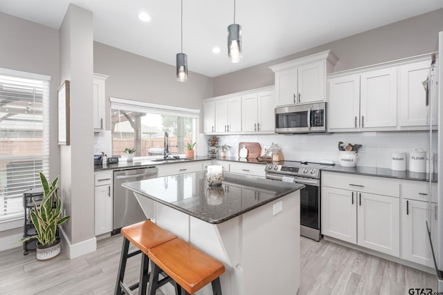 15365 Spring Oaks Dr, Lindale, TX 75771 - kitchen with appliances with stainless steel finishes, light wood-type flooring, a center island, white cabinets, and backsplash