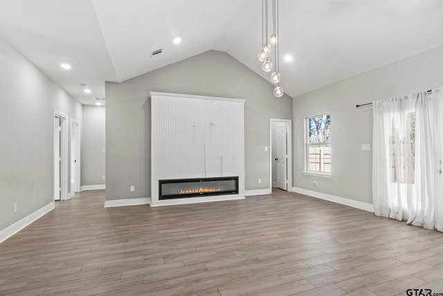 unfurnished living room with a large fireplace, high vaulted ceiling, and light hardwood / wood-style floors