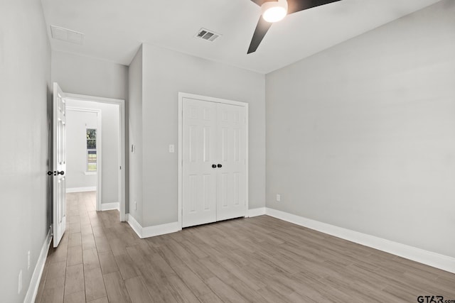 unfurnished bedroom featuring light wood-type flooring, ceiling fan, and a closet