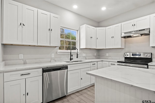 kitchen with stainless steel appliances, white cabinets, sink, light hardwood / wood-style flooring, and range hood