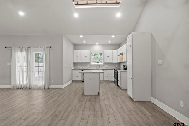 kitchen with a kitchen island, white cabinets, a healthy amount of sunlight, and stainless steel electric stove