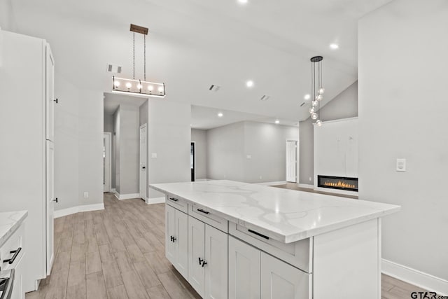 kitchen with white cabinets, hanging light fixtures, light hardwood / wood-style flooring, and a kitchen island