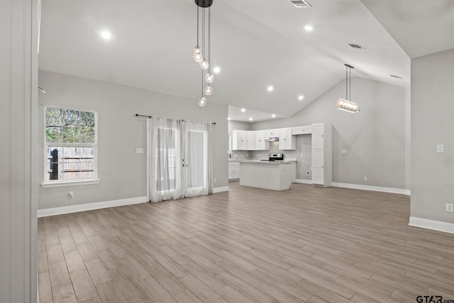 unfurnished living room featuring high vaulted ceiling and light wood-type flooring