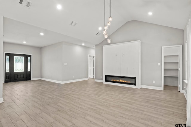 unfurnished living room with high vaulted ceiling, light wood-type flooring, and a large fireplace