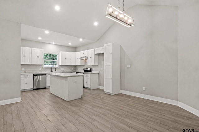 kitchen featuring appliances with stainless steel finishes, decorative light fixtures, light hardwood / wood-style flooring, a center island, and white cabinets