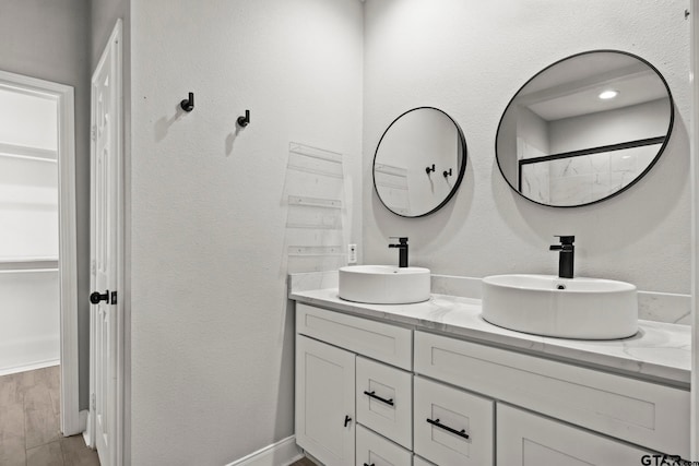 bathroom with walk in shower, vanity, and hardwood / wood-style floors