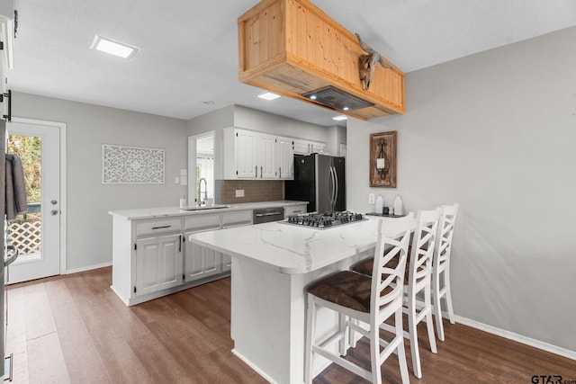 kitchen featuring kitchen peninsula, tasteful backsplash, stainless steel appliances, sink, and white cabinets