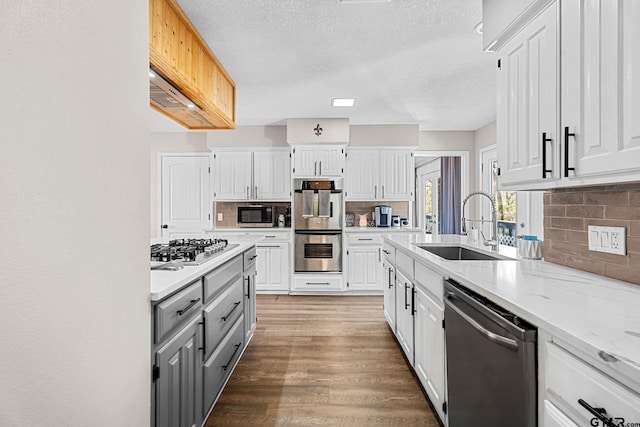 kitchen featuring white cabinetry, sink, light stone counters, decorative backsplash, and appliances with stainless steel finishes