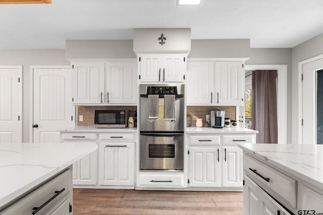 kitchen with appliances with stainless steel finishes, tasteful backsplash, white cabinetry, and light stone counters