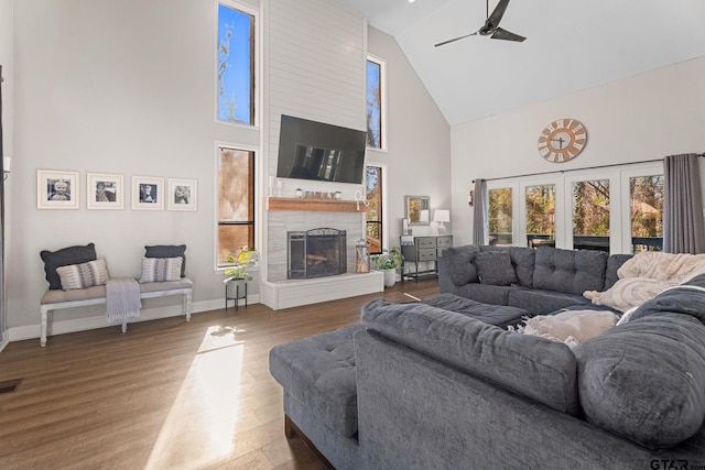 living room featuring hardwood / wood-style floors, ceiling fan, a fireplace, and high vaulted ceiling