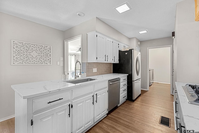 kitchen with light stone countertops, white cabinetry, sink, and stainless steel appliances