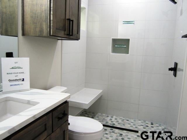 bathroom featuring vanity, toilet, and a tile shower