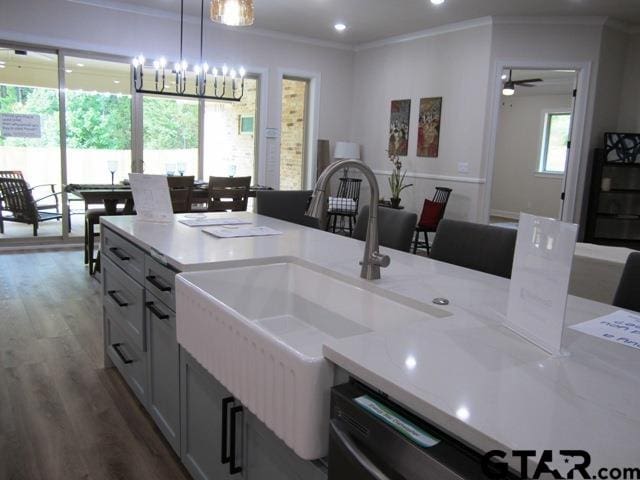 kitchen featuring wood-type flooring, crown molding, pendant lighting, sink, and ceiling fan with notable chandelier