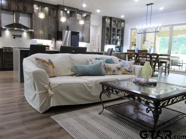 living room with dark hardwood / wood-style flooring, an inviting chandelier, and crown molding