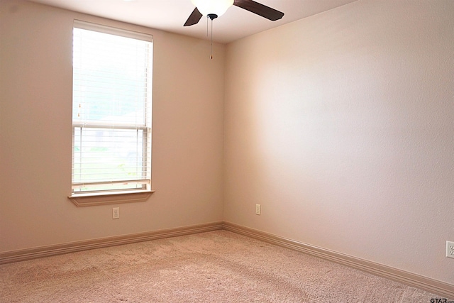 carpeted spare room featuring ceiling fan and plenty of natural light