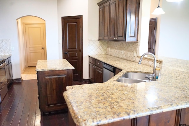 kitchen featuring stainless steel appliances, dark hardwood / wood-style floors, light stone countertops, pendant lighting, and sink