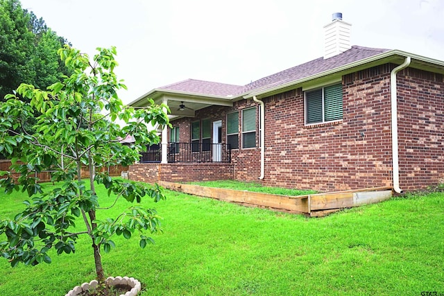 view of side of home with a lawn and ceiling fan