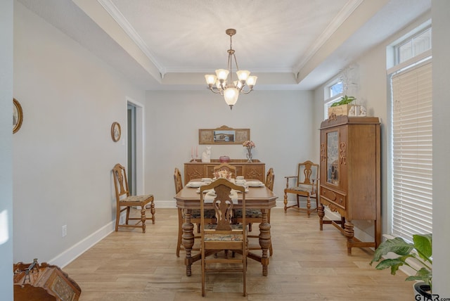 dining area featuring light wood-type flooring, an inviting chandelier, and a tray ceiling