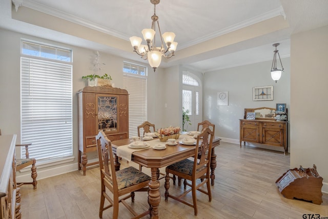 dining room with an inviting chandelier, crown molding, light hardwood / wood-style flooring, and a tray ceiling