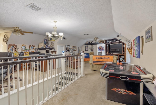 playroom featuring lofted ceiling, ceiling fan with notable chandelier, and a textured ceiling