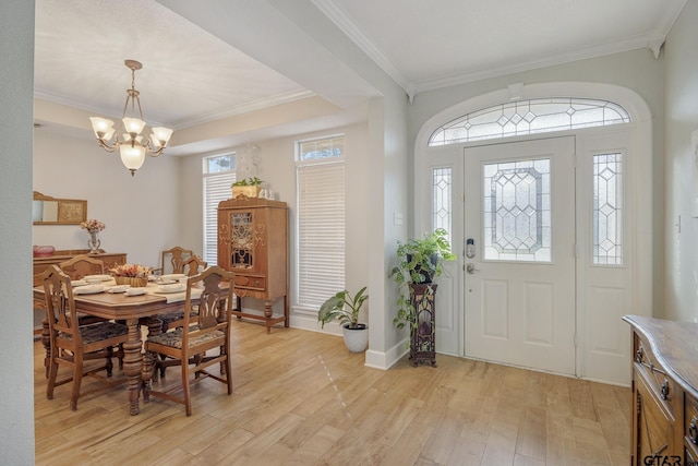 foyer with ornamental molding, a chandelier, and light wood-type flooring