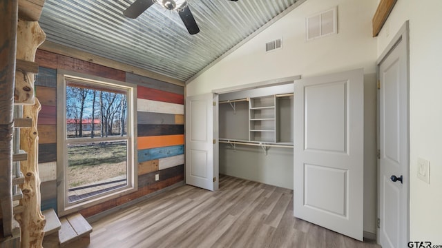 unfurnished bedroom with ceiling fan, lofted ceiling, and light wood-type flooring