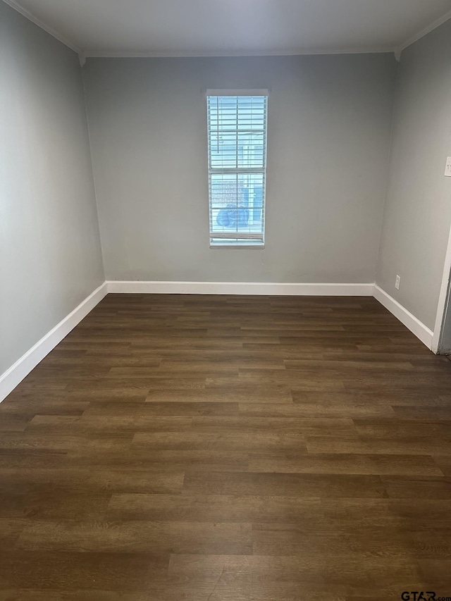 empty room featuring baseboards, dark wood-style flooring, and ornamental molding