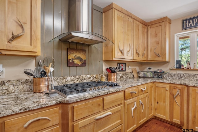 kitchen featuring dark hardwood / wood-style flooring, stainless steel gas cooktop, wall chimney exhaust hood, light stone countertops, and light brown cabinetry