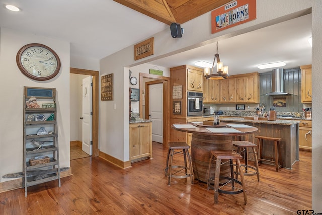 kitchen with hardwood / wood-style floors, wall chimney exhaust hood, oven, and a kitchen island