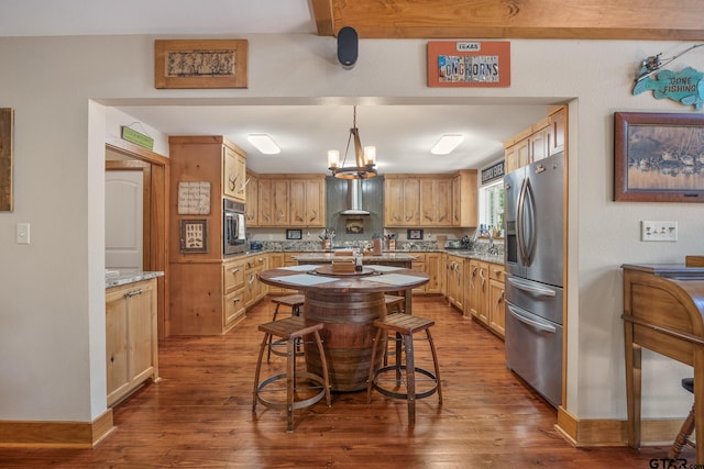 kitchen featuring light stone counters, stainless steel appliances, decorative light fixtures, a notable chandelier, and dark wood-type flooring