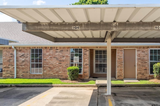 415 Thigpen Dr, Tyler, TX 75703 - doorway to property with covered parking, brick siding, and a shingled roof