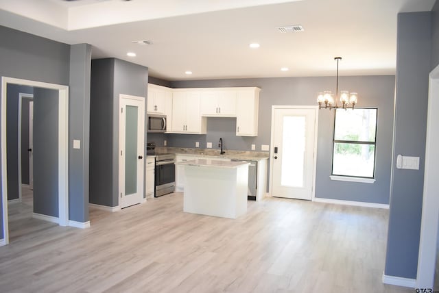 155 Ruby Ln, Nacogdoches, TX 75965 - kitchen featuring stainless steel appliances, light countertops, light wood-type flooring, a kitchen island, and white cabinetry