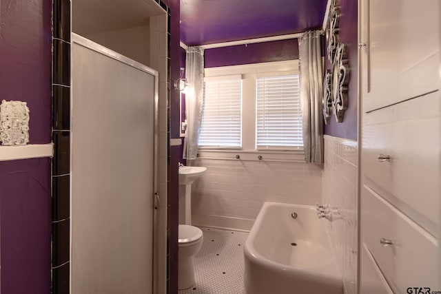 full bathroom featuring a tub to relax in, tile walls, toilet, tile patterned flooring, and walk in shower