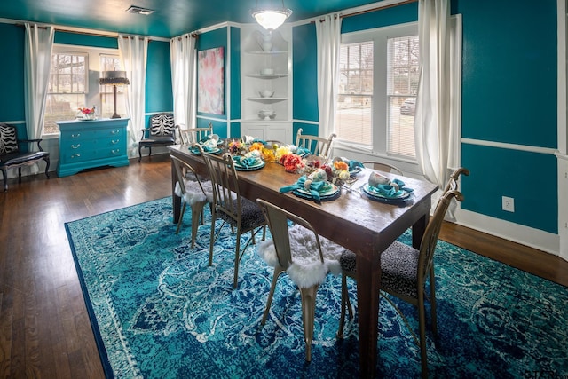 dining room with dark wood finished floors, visible vents, and a healthy amount of sunlight