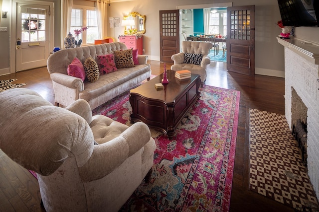 living area with a fireplace, baseboards, and wood finished floors