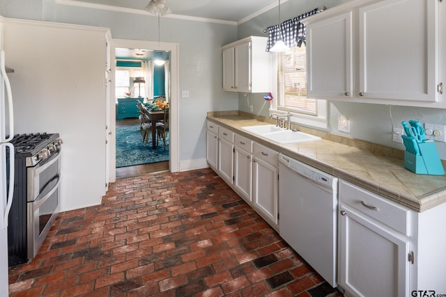 kitchen featuring dishwasher, brick floor, crown molding, double oven range, and a sink