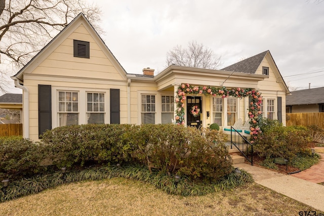 view of front of property with a shingled roof, a chimney, and fence